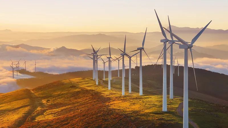 Wind turbines in a vast field at dusk with dramatic sky